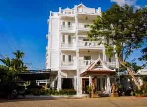 a white building with a tree in front of it at The Blanc Residence in Siem Reap