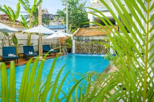 a swimming pool with blue chairs and umbrellas at The Blanc Residence in Siem Reap