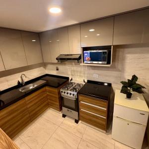 a kitchen with a stove and a sink and a microwave at Depar 1 Dormitorio F in Cochabamba
