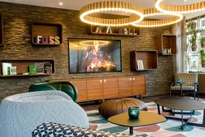 a living room with a tv on a brick wall at Motel One Essen in Essen