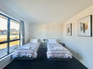 two beds in a room with a window at Star River in Lake Tekapo