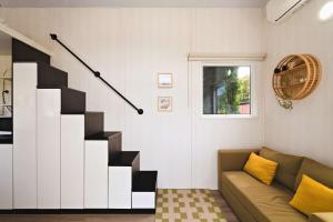 ein Wohnzimmer mit Treppe und Sofa in der Unterkunft The Perch by Tiny Away in Korweinguboora