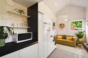 ein kleines Wohnzimmer mit Sofa und Fernseher in der Unterkunft The Perch by Tiny Away in Korweinguboora + 16 Fotos