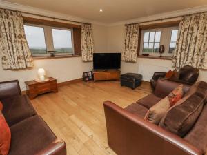a living room with couches and a flat screen tv at Long Cart Cottage in Embleton