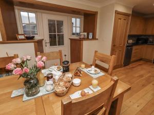 a kitchen and dining room with a wooden table with flowers at Long Cart Cottage in Embleton