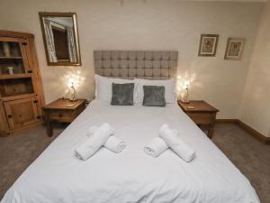 a bedroom with a large white bed with slippers on it at Long Cart Cottage in Embleton +40 photos