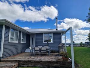a house with a deck with a table and chairs at Country Harbourside Escape in Whakapirau