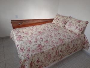 a bedroom with a bed with a floral bedspread at Vila Bárbara superior in Araruama