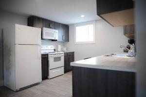 a kitchen with a white refrigerator and a sink at Warm and Welcoming Basement in Dieppe +11 photos
