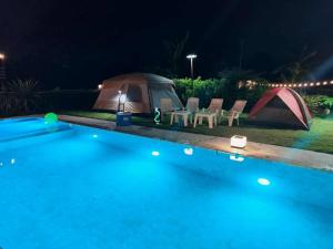 a tent and chairs next to a swimming pool at night at Kitchaview Poolvilla พูลวิลล่า เชียงราย in Chiang Rai