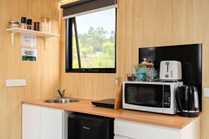 a kitchen counter with a microwave and a sink at Bunjil by Tiny Away in Steels Creek