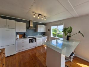 a kitchen with white cabinets and a potted plant on a counter at Country Harbourside Escape in Whakapirau +10 photos