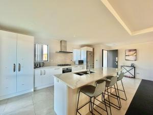 a kitchen with white cabinets and a large island with bar stools at Star River in Lake Tekapo