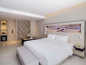 a bedroom with a large white bed and a large painting at Novotel Phuket City Phokeethra in Phuket