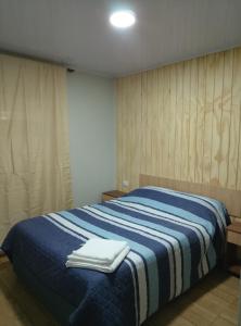 a bedroom with a blue and white bed with towels on it at Apartamentos 22 de mayo in Puerto Montt +13 photos
