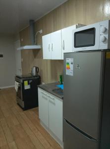a kitchen with a refrigerator and a microwave at Apartamentos 22 de mayo in Puerto Montt