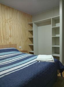 a bedroom with a bed with a blue comforter and shelves at Apartamentos 22 de mayo in Puerto Montt