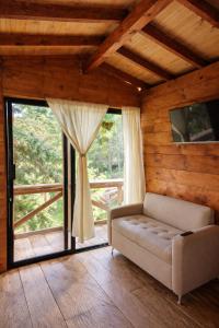 a living room with a couch and a large window at Refugio Natural - Guarne - Cabañas Ecológicas con Jacuzzi e hidromasaje in Guarne