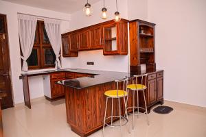 a kitchen with wooden cabinets and bar stools at Windsor in Kandy