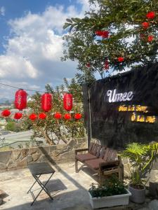 a bench and a sign with red lanterns and flowers at Umee Stayin Đà Lạt in Da Thanh