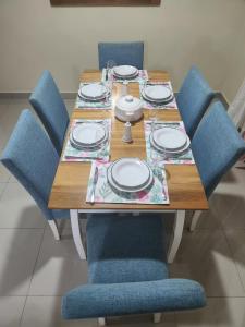 a wooden table with blue chairs and a table with plates at Amazing Three Bedrooms House in La Romana