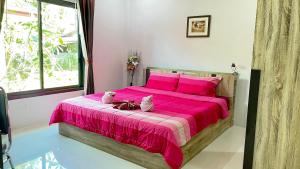 a bedroom with a pink bed with two stuffed animals on it at Abbas House by Swiss Chalet, 2-room Cottages in Krabi