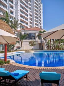 a swimming pool with two chairs and umbrellas at Doubletree By Hilton Sanya Bay in Sanya