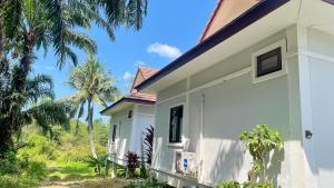 a white house with palm trees in the background at Abbas House by Swiss Chalet, 2-room Cottages in Krabi