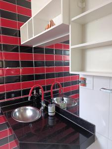 a kitchen with two sinks and red and black tiles at Cantinho da vovó Sol in Cabo Frio +13 photos