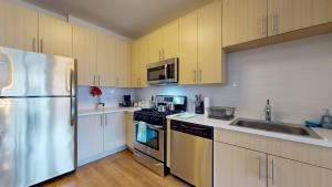 a kitchen with white cabinets and a stainless steel refrigerator at Stylish Home with Free Parking in Stamford