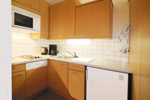 a kitchen with wooden cabinets and a sink at Ferienapartments Birkenhof in Döbriach