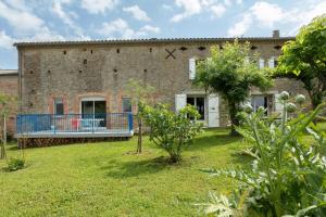 a large brick building with a blue balcony in a yard at Perets petit in Montégut-Lauragais