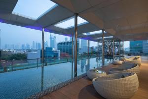 a pool on the roof of a building with chairs at Morrissey Hotel in Jakarta