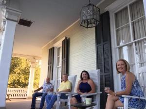 un grupo de personas sentadas en el porche de una casa en Dansereau House, en Thibodaux