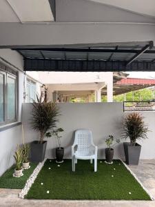 a white chair sitting on a lawn with plants at PRS Homestay in Chemor