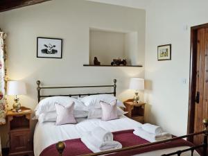 a bedroom with a bed with white sheets and pink pillows at Oak Tree Cottage in Kirkbymoorside