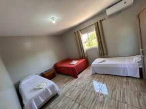 a small room with two beds and a window at Chácara Tuler in Foz do Iguaçu