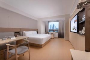 a hotel room with a bed and a desk and a tv at JI Hotel Nanjing Gulou Square in Nanjing