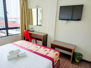 a hotel room with a bed and a desk and a television at New Palace Inn in Miri
