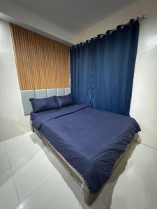 a bed with blue sheets and blue curtains in a room at Jo Condotels at Persimmon Tower3 in Cebu City