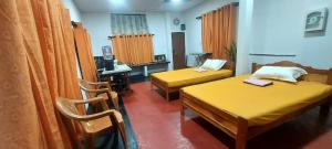 a room with two beds and a desk with a computer at Bird Nest Homestay in Jaffna