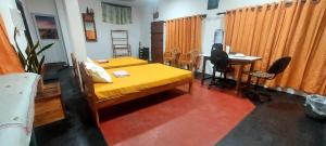 a bedroom with a yellow bed and a desk and a desk at Bird Nest Homestay in Jaffna