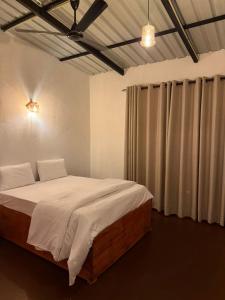 a bedroom with a bed with white sheets and curtains at Mount Boutique Villa in Kandy