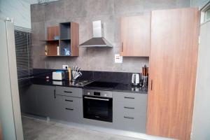 a kitchen with black counter tops and wooden cabinets at Wangu Urban in Mpemba