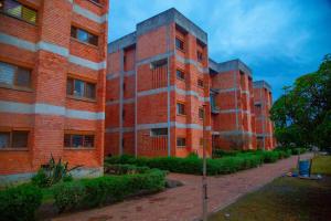 two tall red brick buildings on a street at Wangu Urban in Mpemba