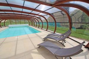 an indoor swimming pool with two chairs and a swimming pool at Brenac in Eymoutiers
