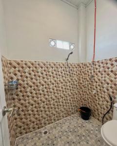 a bathroom with a shower with a tile wall at Caesarea Guesthouse in Berastagi +48 photos