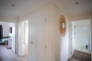a hallway with white walls and a mirror on a wall at Great for Couples - Families - Groups in Mangawhai +26 photos