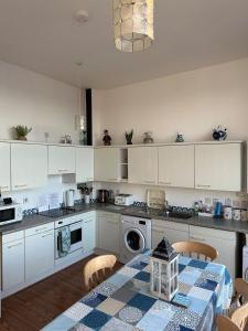 a kitchen with white cabinets and a table with a table cloth at Seaside Penthouse 2 in Largs