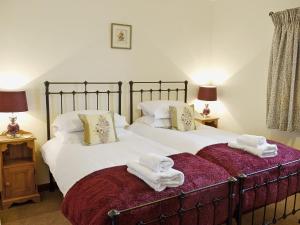 two beds with towels on them in a bedroom at Oak Tree Cottage in Kirkbymoorside